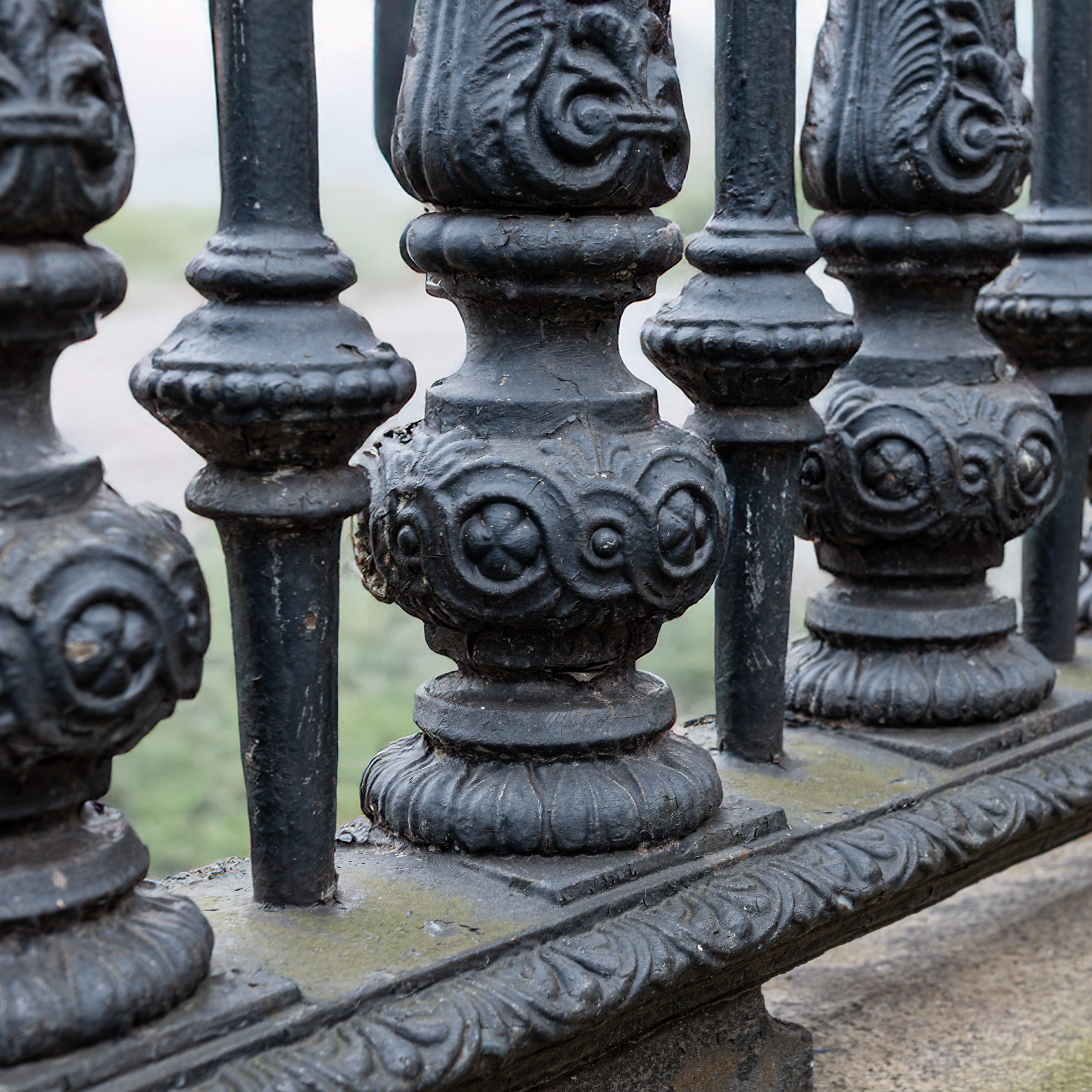 Close-up detail of the ornate Victorian cast iron perimeter fencing at the British Museum in London, showing decorative balusters with acanthus leaf caps, medallion-studded mid-sections, and layered base moldings on a overcast day.