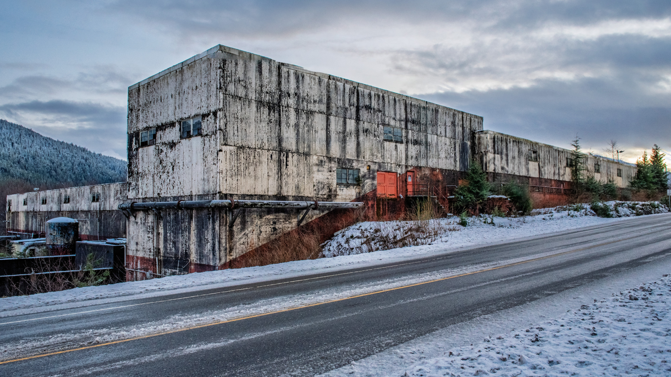 Ruins of the Ward Cove Pulp Mill in Ketchikan, Alaska, showing deteriorating steel and concrete structures being reclaimed by the surrounding Southeast Alaska wilderness.